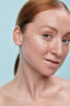 Droplets of Wonder Eye Cream with hyaluronic acid dotted on a glowing face, to show lightweight, hydrating texture