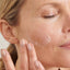 Woman with bright, clear skin cleansing her face and removing makeup with Pure Skin Face Wash