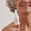 Smiling woman with radiant, mature skin holding bottle of Wonder Eye Cream