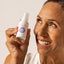 Azelaic acid serum to reduce hyperpigmentation, held by smiling midlife woman